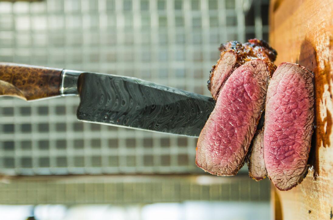 Damascus knife cutting meat