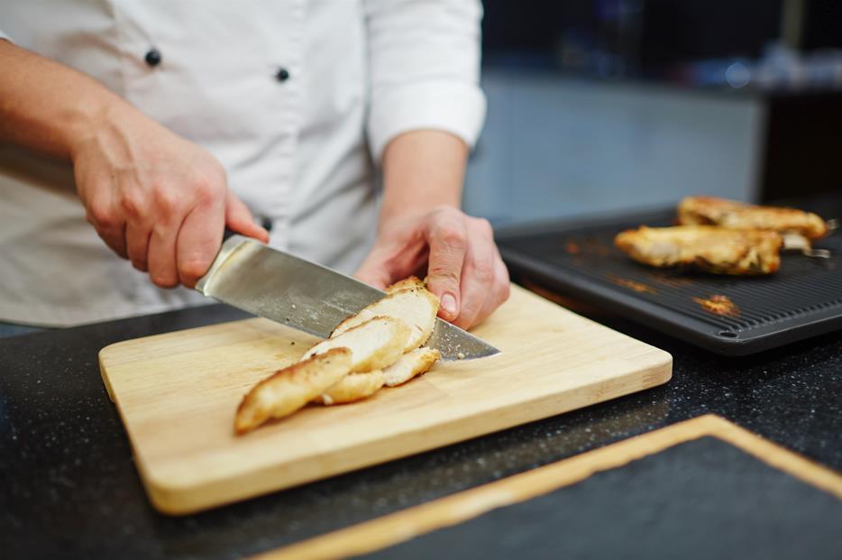 Knife cutting cooked chicken