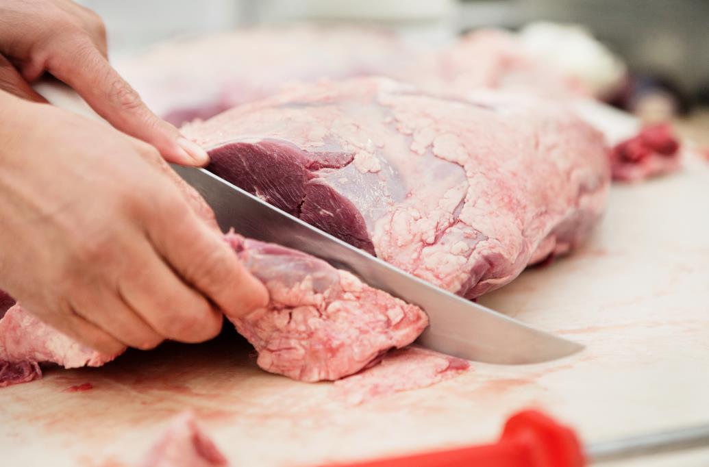 Carving knife cutting raw meat 