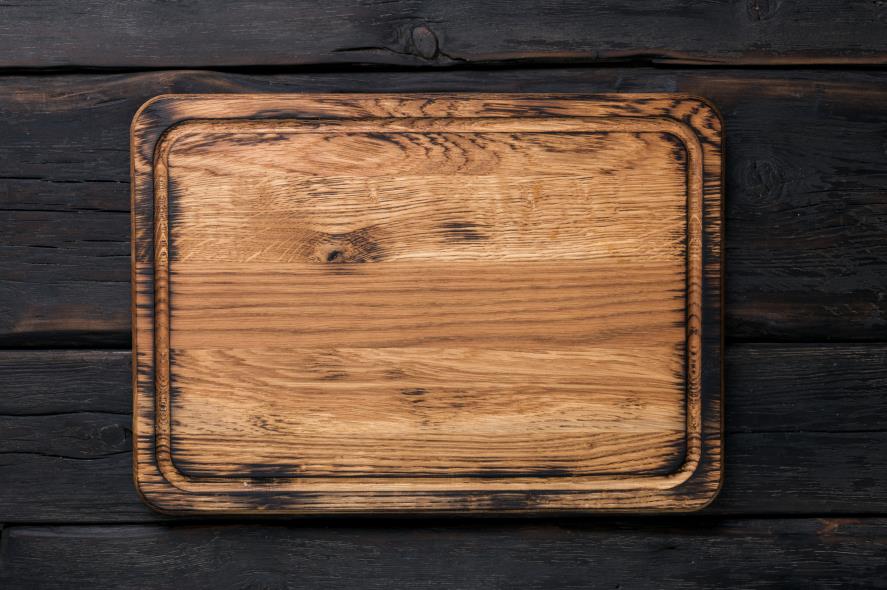 Wooden cutting board on dark wood background