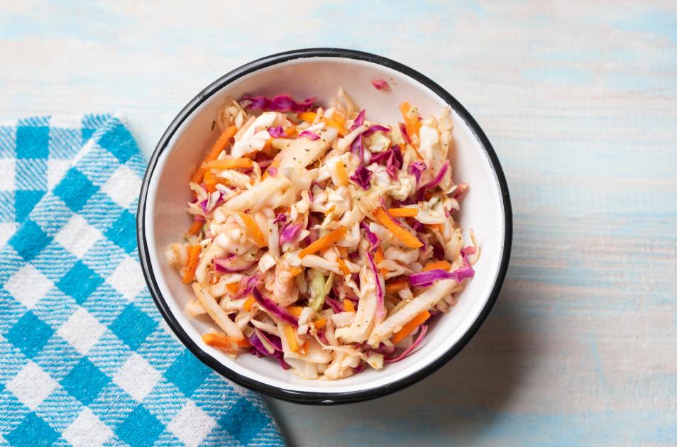 Coleslaw with vinegar and oregano on wooden background