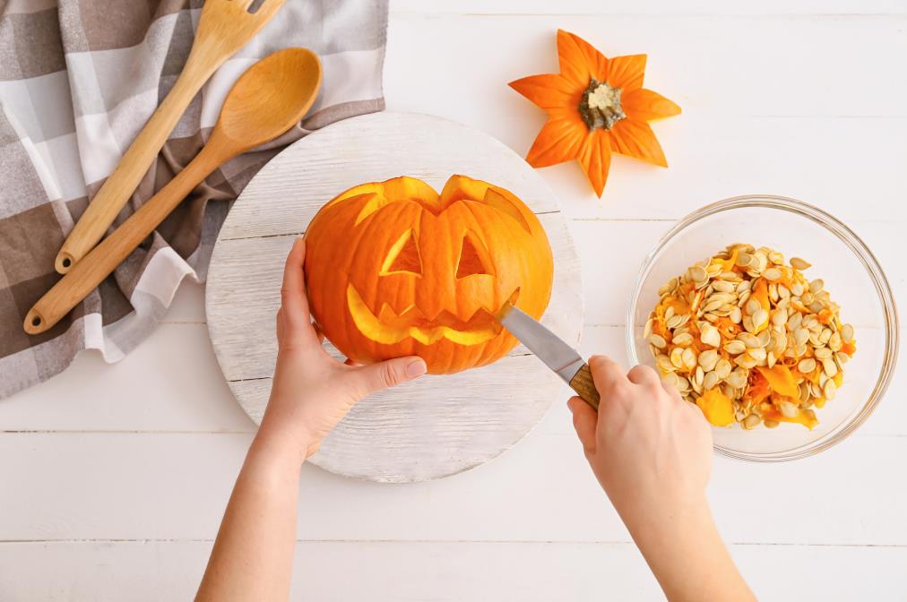 Woman carving pumpkin for Halloween at table
