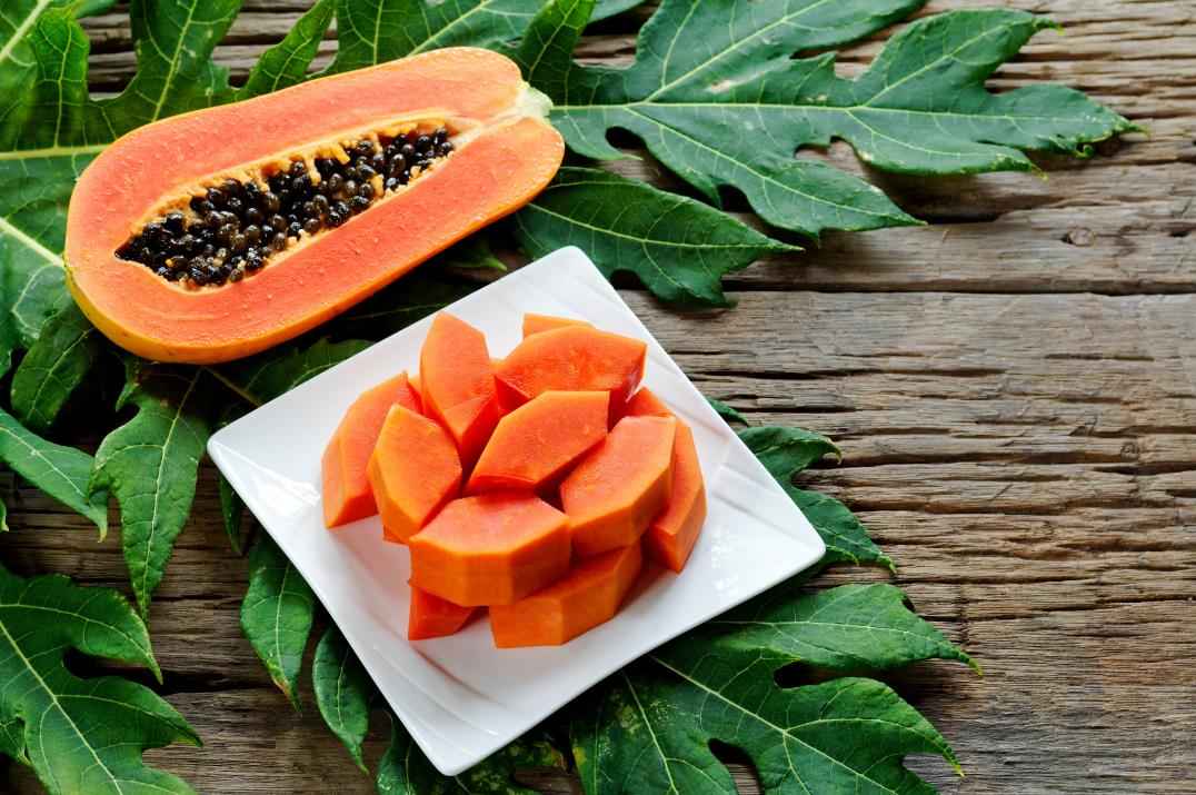 Sliced Ripe papaya fruit on white plate on wood background