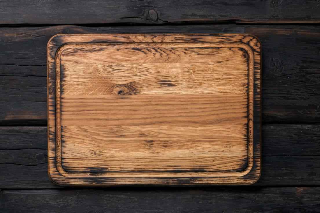Empty cutting board on a dark wooden table
