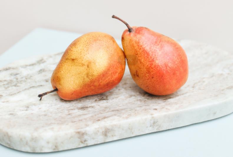 A pair of pear on top of marble cutting board