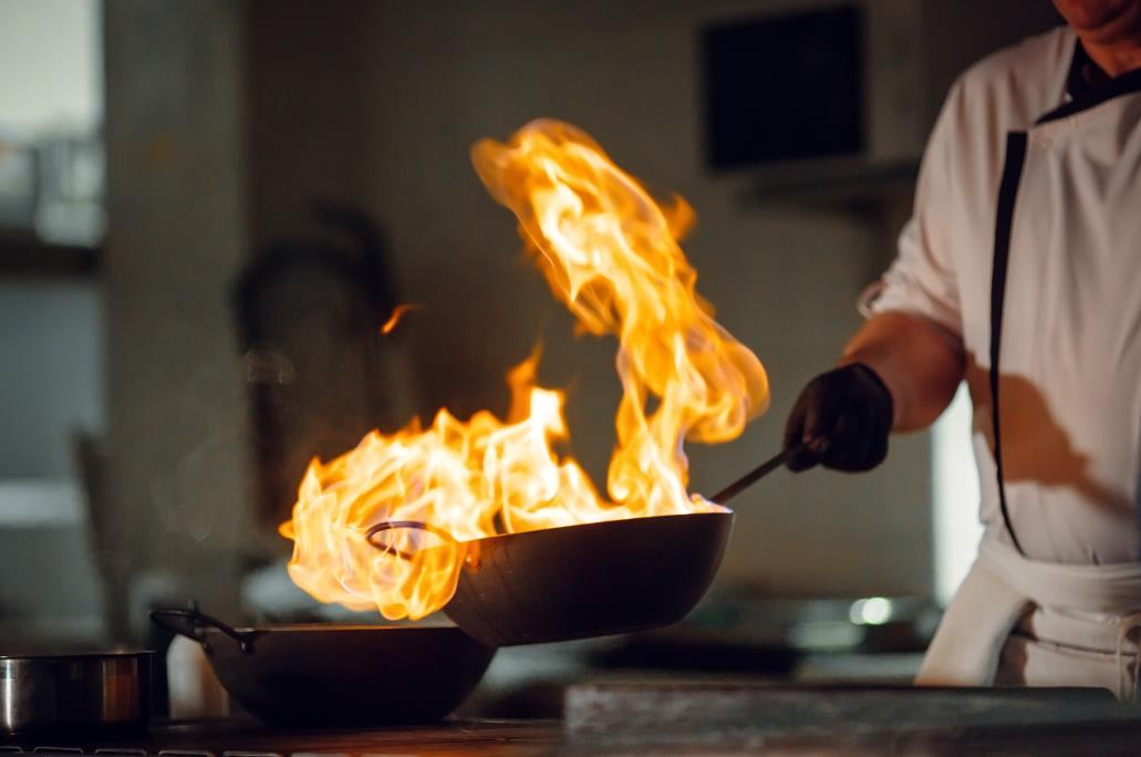 chef holding a pan on fire