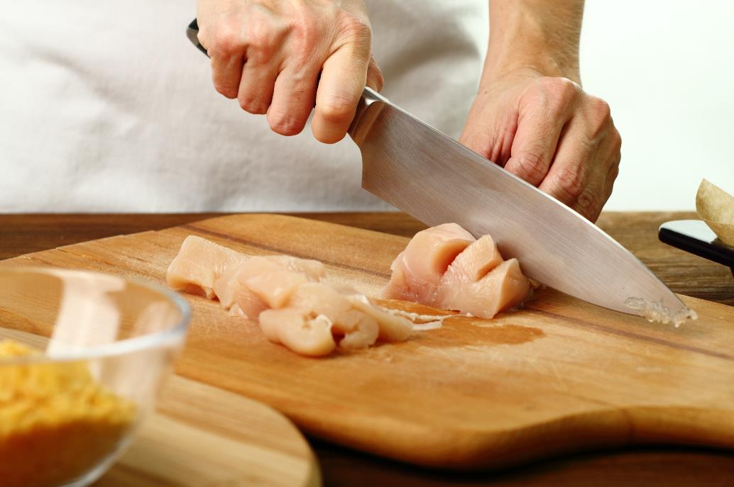 couper un filet de poulet sur une planche à découper en bois