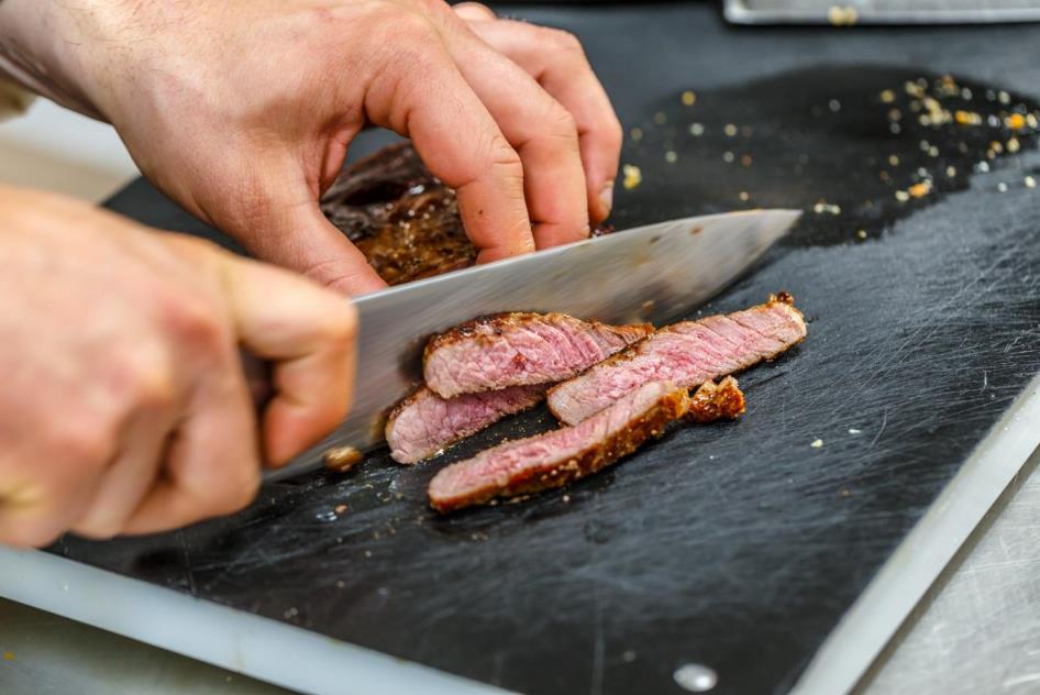 couper de la viande sur une planche à découper en plastique