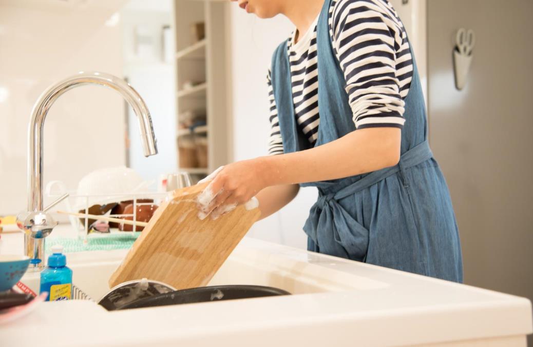 women wearing apron cleaning washing a cutting board