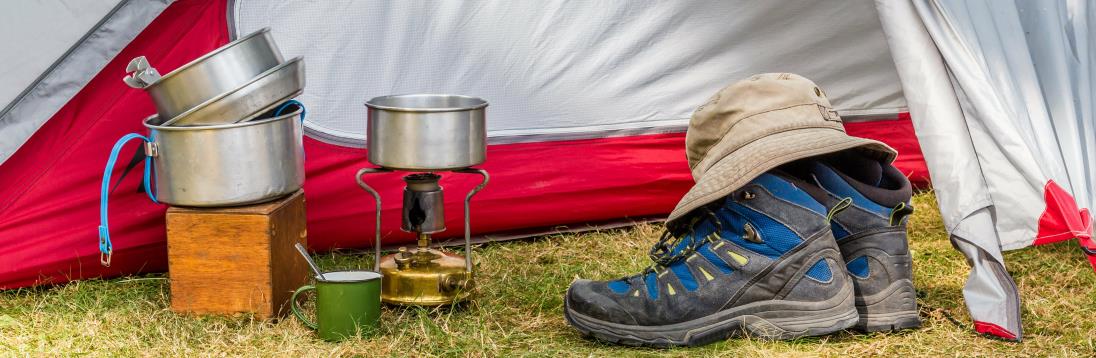 Essential cooking equipment in front of a colorful tent on a campsite