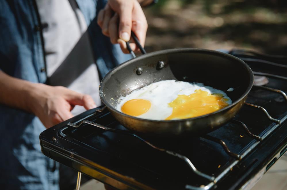 men making eggs on camping stove