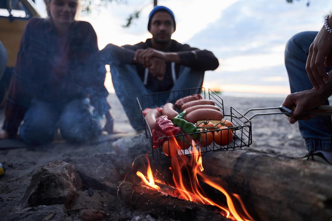 Friends grill over a campfire food in grill basket
