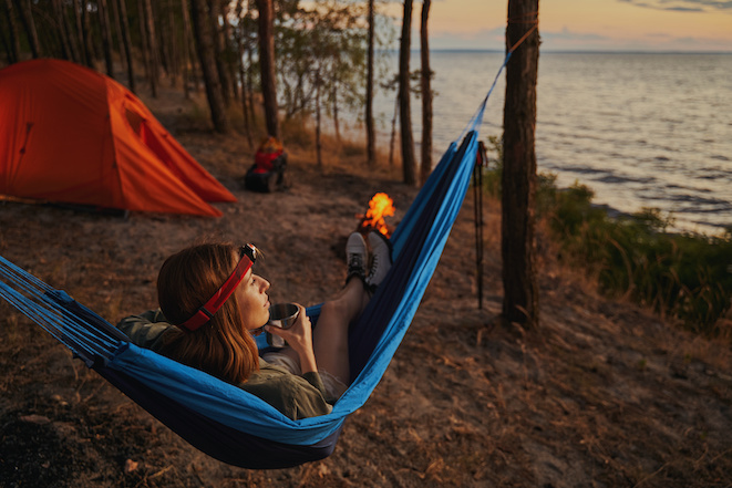 Lady laying in a hammock with metal teacup