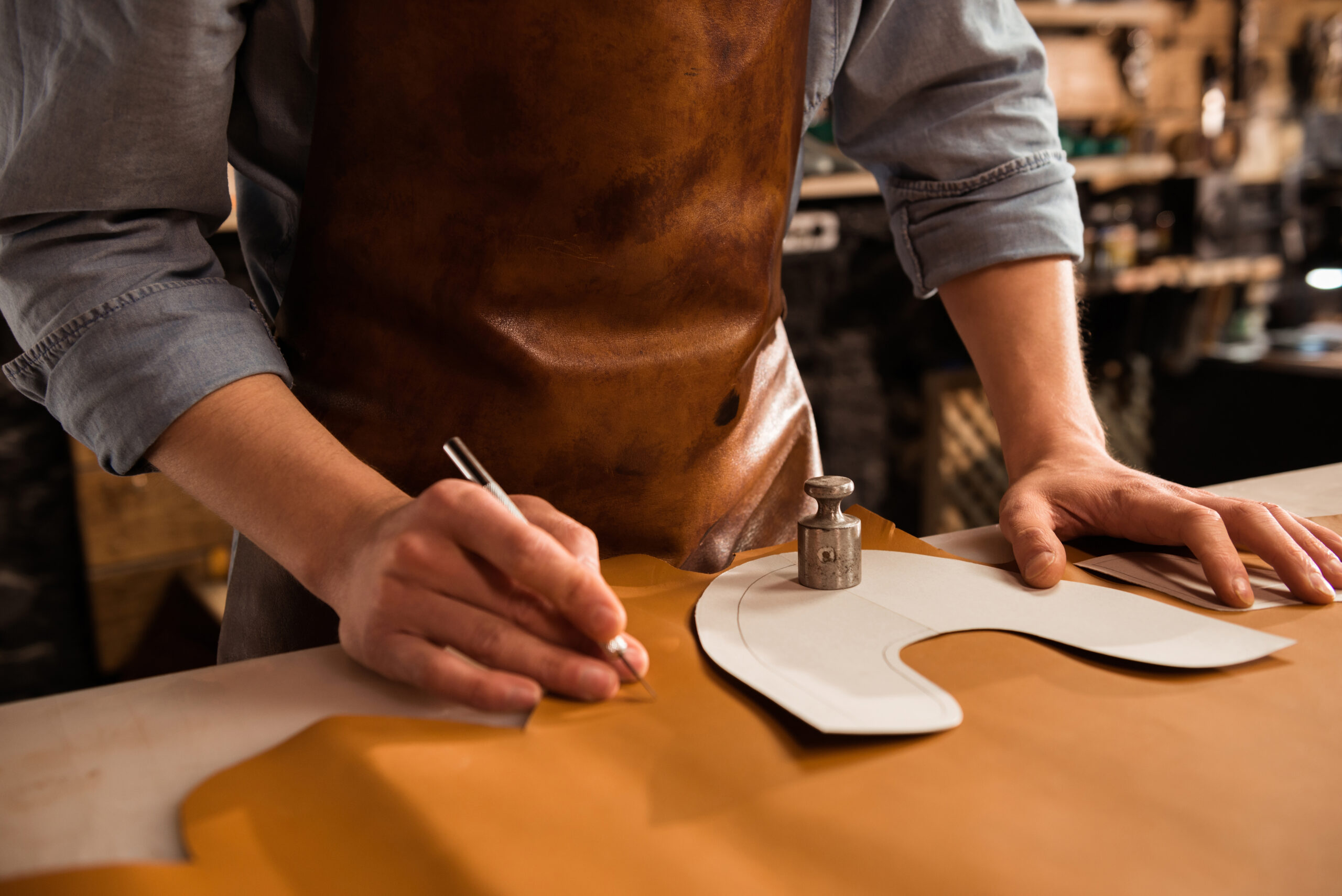 leather maker carving out the outline of the leather sheath