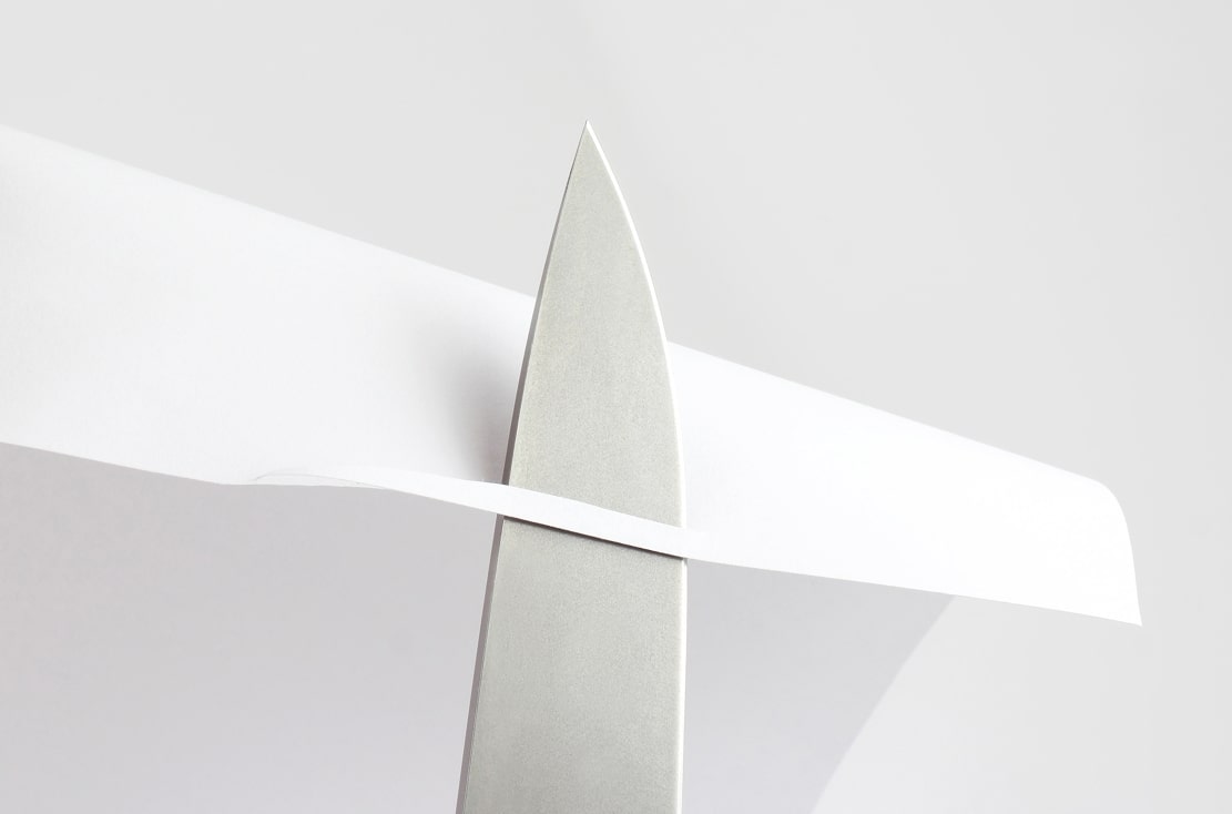 image of steel cutting through white paper