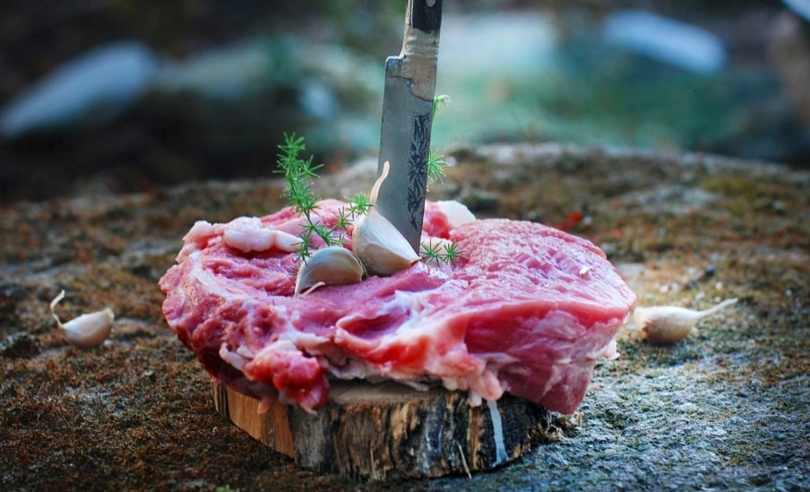 butcher knife sticking in red meat outdoor 